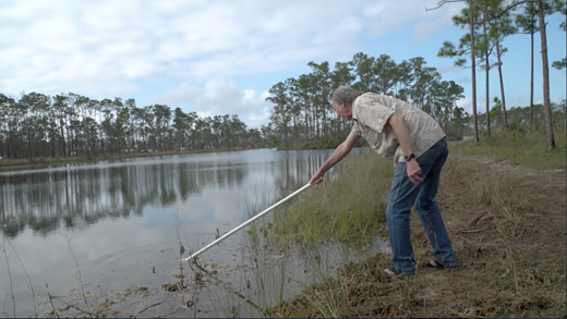 Nonindigenous algae specialist Larry Brand takes water samples to measure the toxins from agriculture that will be consumed by shrimp and fish that will later be consumed by humans in Poison Water (2018), a film in SwampScapes (2018), produced and directed by Elizabeth Miller, Kim Grinfeder, and Juan Carlos Zaldivar.