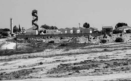 View of a portion of the Gush Katif settlement bloc. The cleared and denuded area in front of the settlement functioned as a security barrier and made it easier for sentries in the tower (center) to spot movement near the settlement. The image shows how land was taken out of circulation, removed from any agricultural use, and rendered off-limits to Gazans. (2005, photo by the author)