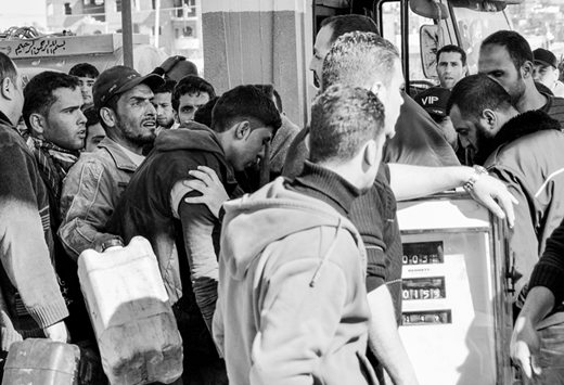 Gazans jostle for gasoline at one of the few operational service stations near Bayt Hanun while a policeman with his hand on the shoulder of one person tries to keep order. (2012, photo by the author)