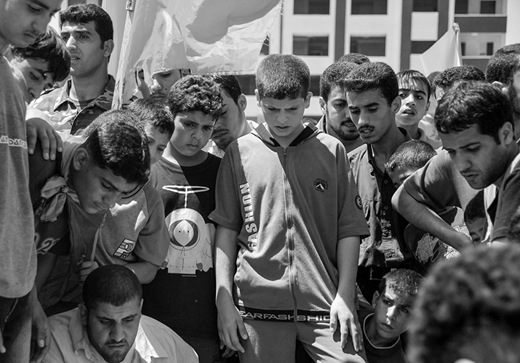 Youth in Gaza City peering into the just-lowered coffin of a ten-year old killed by an “errant” Israeli missile strike on a car during Operation Summer Rains. (2006, photo by the author)
