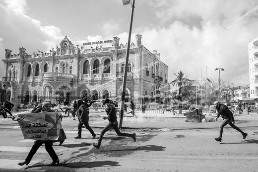 Palestinians protesting the Trump administration's Middle East “peace plan” run from Israeli projectiles in front of Bethlehem's Jacir Palace Hotel. (29 January, Musa al Shaer/AFP via Getty Images)