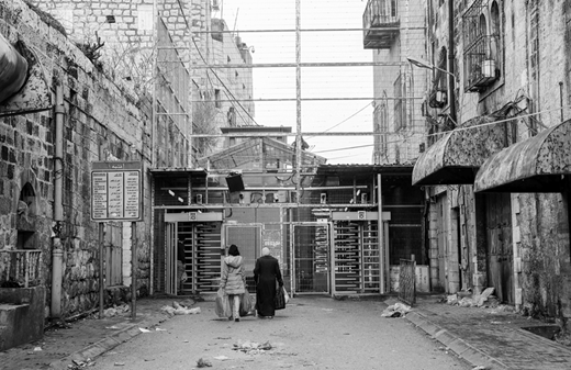 Two Palestinian women in the West Bank city of Hebron approach an Israeli checkpoint to cross into Shuhada Street, once Hebron's main marketplace and thoroughfare. Israeli forces have all but closed off Palestinian access to Shuhada Street since 1994. (13 January, Emmanuel Dunand/AFP via Getty Images)
