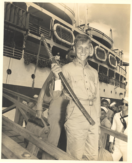 “Some troops disembark with booty captured from the enemy: young man with Japanese sword.” Companion photograph published in Pearl Harbor Banner, 7 January 1944, p. 5, shows wounded from the Battle of Tarawa being unloaded from the same ship. Source: Series: Box 4 FF 7, PHNY: Return of the wounded, departure of troops Undated. Cat. no. PHNY 144, Robert F. Walden Collection (1936–1991), University of Hawai‘i at Mānoa Library.